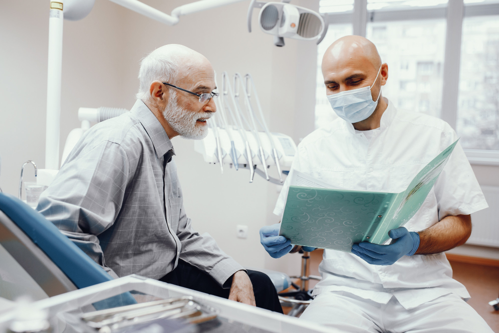 An elderly gentleman being advised by a dentist with his medical charts