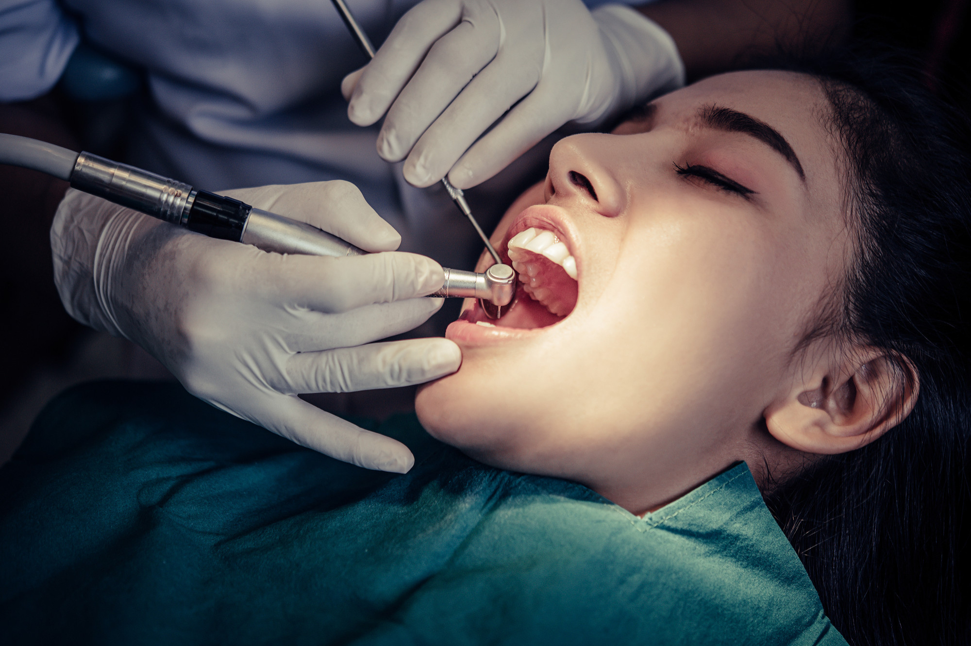 A young lady under the lights on a dentist’s chair undergoing a procedure